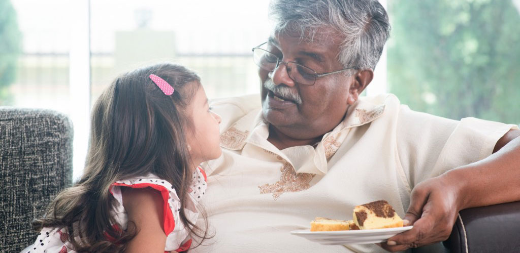 indian-grandfather-eating-cake-with-little-girl